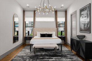 A modern bedroom with a large bed, bedside tables, a mirror, and a chandelier. - Luxe Getaway with Hot Tub (Nashville)