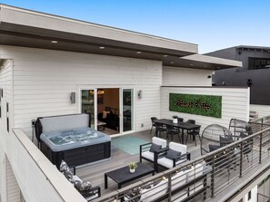 Eine moderne Außenpatio mit Whirlpool, Sitzgruppe und einer an der Wand befestigten Schilder.