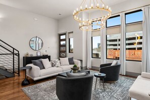 A modern living room with a sofa, armchairs, a coffee table, and a chandelier. - Luxe Getaway with Hot Tub (Nashville)