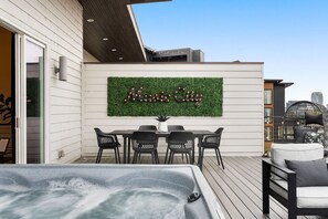 A rooftop patio with a hot tub, outdoor seating, and a wall-mounted sign reading 'Music City.' - Luxe Getaway with Hot Tub (Nashville)