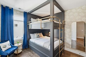 A bunk bed room with a ladder, a small round table with a plant, a blue armchair, and a mirror on the wall. - Luxury Gated Duo Sleeps 24 Karaoke & Rooftop (Nashville)