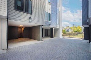A modern building with a covered outdoor area, a paved walkway, and a fenced yard. - Luxury Gated Duo Sleeps 24 Karaoke & Rooftop (Nashville)