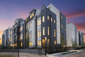 Um edifício residencial moderno de vários andares, com fachada simétrica, grandes janelas e telhado plano.