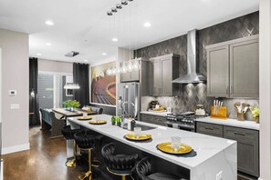 A modern kitchen with a central island, stainless steel appliances, and pendant lighting. - Luxury Gated Duo Sleeps 24 Karaoke & Rooftop (Nashville)