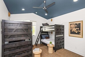 Une petite pièce avec un lit superposé, un ventilateur de plafond et une échelle.