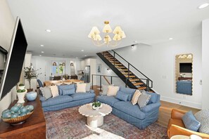 Un salon spacieux avec un canapé d’angle, une table basse et un escalier menant à l’étage supérieur.