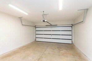 Eine Garage mit weißer Garagentür, Neonbeleuchtung und einem an der Decke befestigten Projektor.