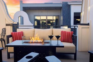 An outdoor seating area with a fire feature, a sofa, and two chairs. - Sleeps 24! Broadway Views, Rooftops & Karaoke (Nashville)