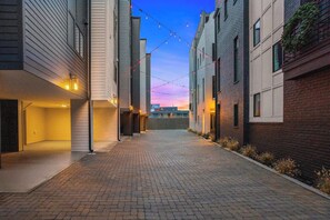 A narrow alleyway with brick paving, flanked by modern buildings with large windows and string lights. - Sleeps 24! Broadway Views, Rooftops & Karaoke (Nashville)