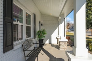 A covered porch with a bench, a potted plant, and a stone wall. - New Hot Tub, Spacious, Near Downtown (Nashville)