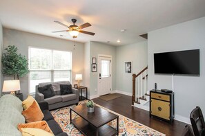 A living room with a sofa, coffee table, and a TV mounted on the wall. - Relaxing 2 BD/2.5 BA Nash Home (Nashville)