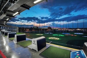 A golf driving range with multiple tee boxes and a well-lit driving area. - East Nash Cottage 3 Miles to Downtown! (Nashville)