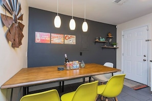 A dining area with a wooden table, bright yellow chairs, and hanging pendant lights. - East Nash Cottage 3 Miles to Downtown! (Nashville)