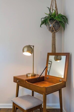 Un escritorio de madera con un espejo, una lámpara y una planta.
