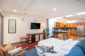 Una habitación de hotel moderna con una cama grande, televisión, escritorio y kitchenette.