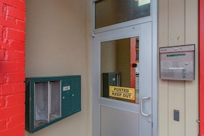 Eine Tür mit einem Schild 'POSTED NO TRESPASSING KEEP OUT', einem grünen Briefkasten und einem Verteilerkasten mit Tastatur.