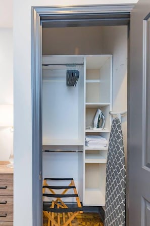 Ein begehbarer Kleiderschrank mit offenen Regalen, einer Kleiderstange und einer Holzleiter.