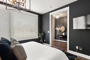 Ein Schlafzimmer mit einem Bett, einer Topfpflanze und einem an der Wand befestigten Fernseher.