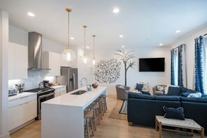 A modern kitchen with a central island, bar stools, and pendant lighting. - 2 Side by Side Homes with Rooftops -Sleeps 24 (Nashville)
