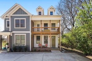 A two-story house with a front porch, a balcony, and a small garden area. - Spotless Gem | Hot Tub | 15 Min to Broadway (Nashville)