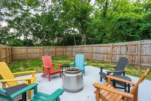 An outdoor seating area with multiple Adirondack chairs and a metal fire pit. - Spotless Gem | Hot Tub | 15 Min to Broadway (Nashville)
