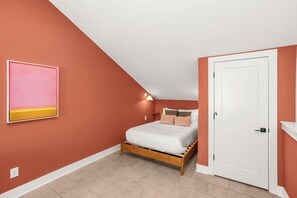 Un dormitorio con una cama, una puerta blanca y un aplique de pared.