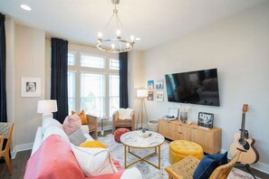 Una sala de estar con un sofá, una mesa de centro, un televisor y una guitarra.