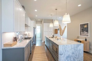 A modern kitchen with marble countertops, pendant lighting, and a central island. - 2 Homes-Sleeps 24-Roof Decks-Grills Near Broadway (Nashville)