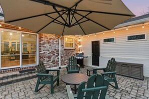 An outdoor patio with a brick wall, a grill, and green Adirondack chairs. - Peaceful Nashville Ranch • A Cozy Place to Unwind! (Nashville)