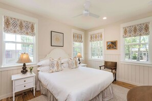 A bedroom with a large bed, two bedside tables, a chair, and a ceiling fan. - Purple Martin: Secluded Forest Birdwatcher (McEwen)