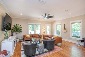 A living room with a sofa set, two armchairs, a coffee table, and a TV mounted on the wall. - Winter Retreat: Hot Tub|Arcade|Near BWAY|Parking (Nashville)