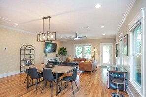 A spacious living area with a dining table, chairs, a sofa, and a television. - Winter Retreat: Hot Tub|Arcade|Near BWAY|Parking (Nashville)