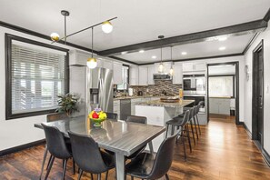 Cocina moderna con electrodomésticos de acero inoxidable, una isla central e iluminación colgante.