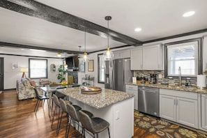 Eine moderne Küche mit Granit-Arbeitsplatten, Edelstahlgeräten und einer zentralen Kochinsel mit Barhocker.