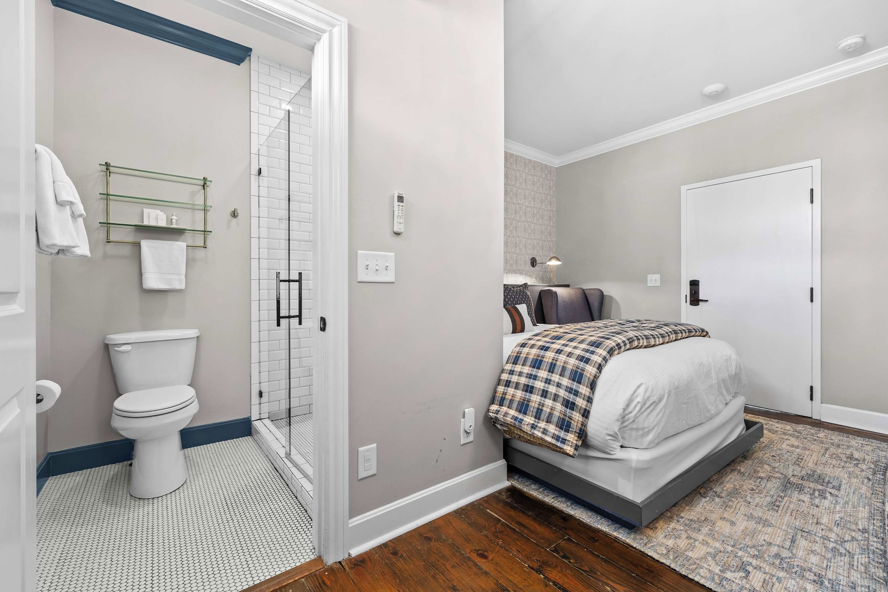 A bathroom with a toilet, a glass shower enclosure, and a towel rack with towels.