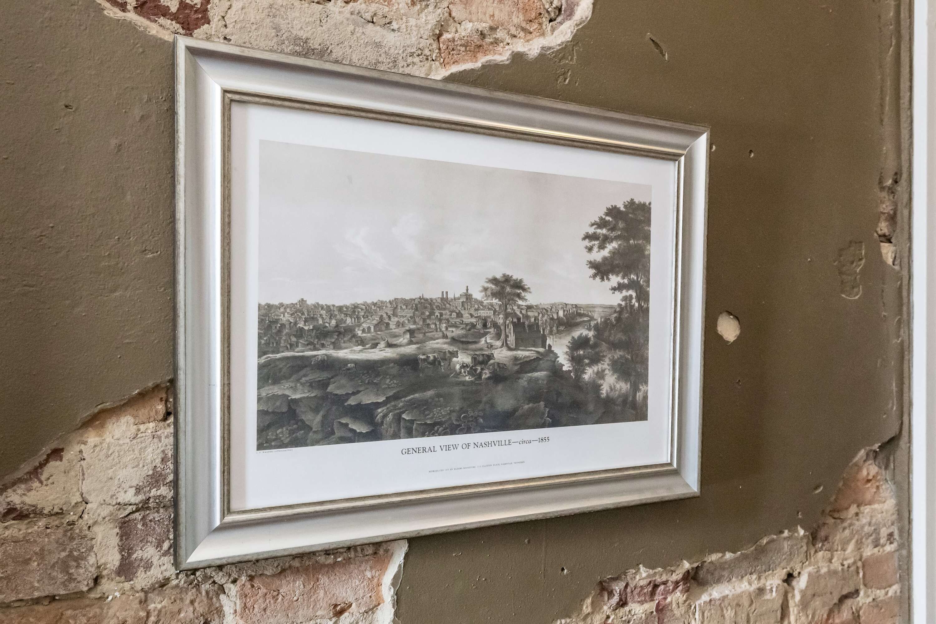 Fotografía en blanco y negro enmarcada de una vista histórica de Nashville alrededor de 1855, montada sobre una pared con textura.