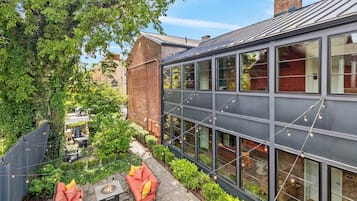 A modern building with large windows, a brick facade, and a courtyard with outdoor seating.
