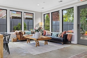 A spacious living room with a leather sofa, a wooden coffee table, and a dining area with chairs.