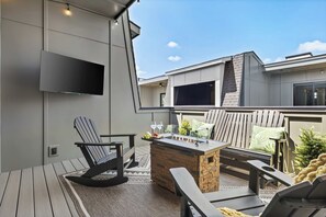 A modern outdoor seating area with a stone bar, Adirondack chairs, and a flat-screen TV mounted on the wall. - Karaoke, Rooftop, Fire Pit -The Ryman (Nashville)