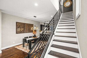 Uma escadaria moderna com degraus de madeira escura e corrimão de metal preto.
