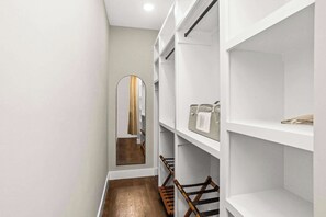 A narrow hallway with white shelving units, a wooden floor, and a mirror on the left. - Gated Luxury in Nashville: Rooftop Views+Fire Pit (Nashville)