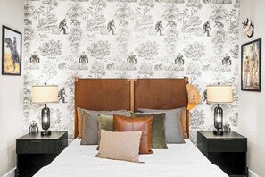 Quarto com cama grande, duas mesas de cabeceira e encosto de cama.