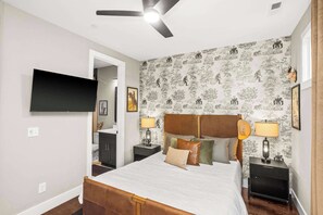 A bedroom with a bed, nightstands, a TV, and a ceiling fan. - Gated Luxury in Nashville: Rooftop Views+Fire Pit (Nashville)