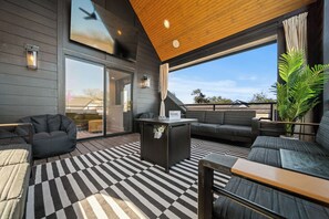 A modern outdoor living area with a checkered floor, a black sofa, a bean bag, and a table. - Rooftop Lounge 2 Miles from Broadway! (Nashville)