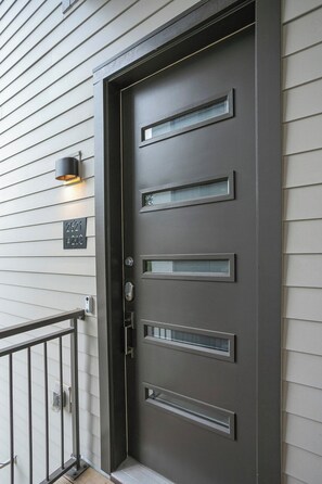 A modern door with a keypad lock, a mailbox, and a light fixture on the wall. - Downtown Lux Condo: South Belle (Nashville)