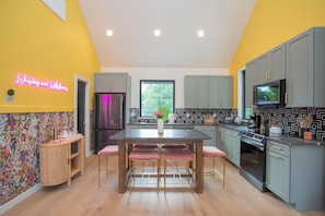 A modern kitchen with a central island, grey cabinets, and a neon sign on the wall. - Bohemian Chic Hot Tub Sleeps 12 (Nashville)