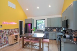 Una cucina moderna con isola centrale, mobili grigi e un neon sulla parete.