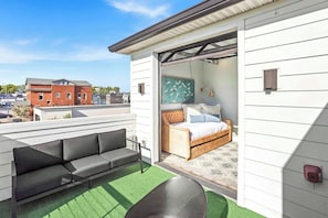 A modern outdoor patio with a sofa and a bed, a green artificial turf floor, and a view of the cityscape. - 2 Homes-Sleeps 24 | Downtown Great for Big Groups! (Nashville)