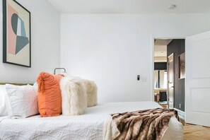 Une chambre à coucher avec un lit, des oreillers, une couverture et un tableau accroché au mur.