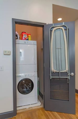 Ein Waschraum mit Waschmaschine und Trockner, einem Bügelbrett sowie Waschmitteln.